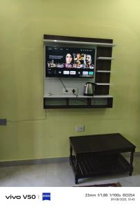 a flat screen tv on a green wall with a table at Pushpanjli grand inn in Ayodhya