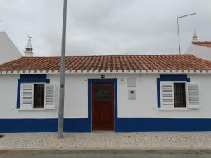 a white and blue house with a red roof at Casa Campo e Praia in Rogil