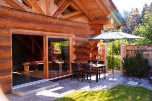 a wooden cabin with a table and an umbrella at Chalet Enzian Bayerwald in Arnbruck +10 photos