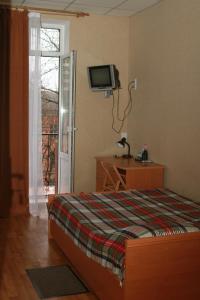 een slaapkamer met een bed en een tv aan de muur bij Эконом Комнаты in Donetsk