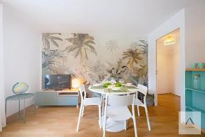 a dining room with a table and white chairs at Le Prieuré in Dinard