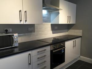 kuchnia z białymi szafkami i czarnym blatem w obiekcie Samuel Place by SG Property Group w mieście Crewe