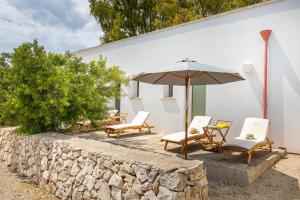 a group of chairs and an umbrella next to a wall at TerreAmare Agriturismo in Porto Cesareo