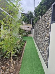 a garden with green grass next to a stone wall at Viajeros Apartelle in Valencia +1 photo