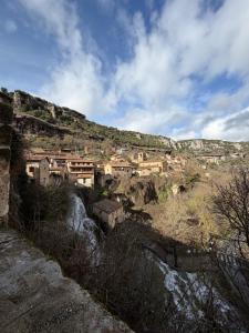 a village on a hill with a river and buildings at El Salto del Agua in Orbaneja del Castillo