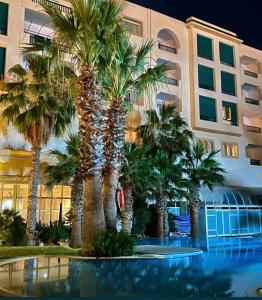 a group of palm trees in front of a building at Yasmina Hotel Appartment in Yasmine