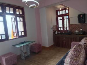 a living room with a couch and a table and windows at Cosmic Buddha Bnb in Gangtok +7 photos
