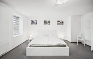 a white bedroom with a bed and two chairs at Gut Barzig in Großräschen