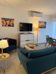 a living room with a blue couch and a tv at La Belle Prise in Matougues