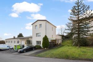a white house with cars parked in a parking lot at Ferienwohnung Bernhard in Wermelskirchen