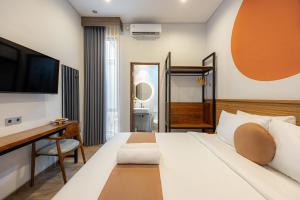 a bedroom with a bed and a desk and a television at Cove Ruma Coliving in Denpasar
