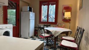 a kitchen with a table and a white refrigerator at La Forge de Paul et Virginie in Mainneville