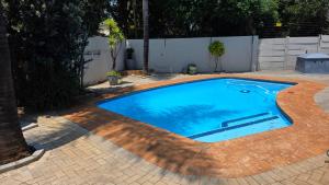 a large swimming pool in a backyard with a brick patio at 78onJean in Centurion