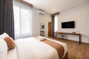a hotel room with a large bed and a flat screen tv at Cove Ruma Coliving in Denpasar