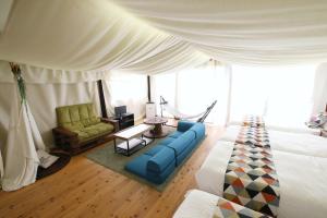 a bedroom with a bed and a couch and a chair at halfGlamping星音 B in Nakijin