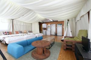 a bedroom with a bed and a couch and a tv at halfGlamping星音 B in Nakijin