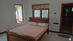 a bedroom with a wooden bed with two windows at White Umbrella - Homestay in Beruwala