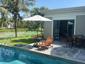 a patio with a table and an umbrella next to a pool at Villa Coastar 002 Hồ Tràm in Ho Tram
