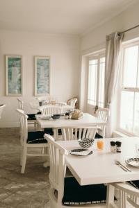 a dining room with white tables and white chairs at Summer House B&B in Gqeberha