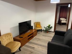 a living room with a tv and a couch and chairs at Alvarenga House in Maia