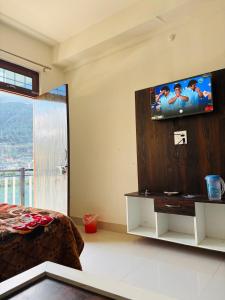 a bedroom with a bed and a television on a wall at The HIGHLIGHT STAY in Uttarkāshi
