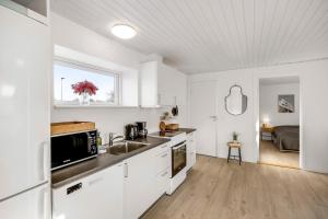 a kitchen with white cabinets and a sink and a bed at FeWo Lille Vidstrup in Vidstrup +7 photos