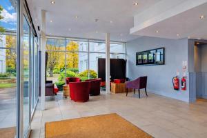 a lobby with red chairs and tables and windows at Manchester Airport Stanley Hotel by Belvilla in Handforth +54 photos