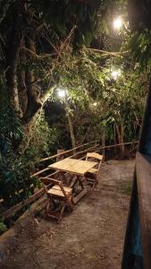a picnic table and two chairs in a forest at night at Pousada Jardins da Gastehaus in Triunfo