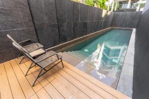 a chair sitting on a deck next to a swimming pool at Heaven Thonglor 36 - Villa in Bangkok
