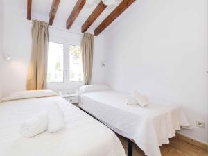 two beds in a white room with a window at Villa Gavines Up in S'Algar