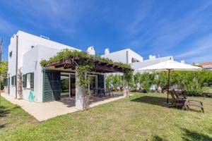 a white building with an umbrella and a yard at Biniancolla Heura in Biniancolla