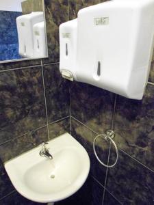 a bathroom with a sink and a paper towel dispenser at Hostel e Pousada Solar in Poços de Caldas