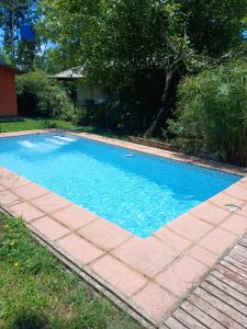 a swimming pool with a brick walkway around it at Cabaña Carmela in Garupá