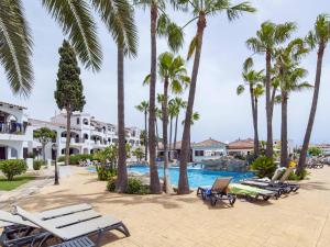 a resort with palm trees and a swimming pool at Siesta Mar Apartamentos in Cala en Porter