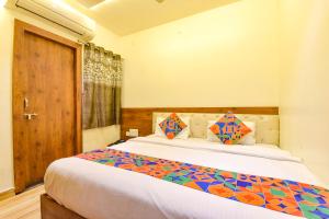 a bedroom with a large bed with colorful pillows at FabHotel Aishwarya in Kota