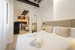 a bedroom with a white bed with towels on it at Escolástica Suites Centro in Granada