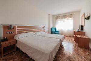 a bedroom with a large bed and a blue chair at Hotel La Familia in El Campello