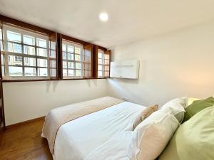 a bedroom with a large bed and two windows at Casa do Castello Chaves in Chaves