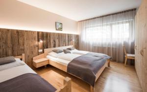Zwei Betten in einem Schlafzimmer mit Holzwänden und einem Fenster in der Unterkunft Bachmannhof in Feldthurns