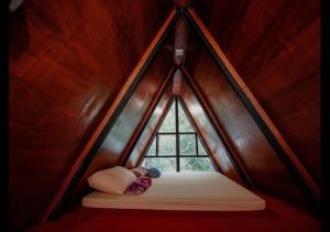 a small window in a wooden room with a bed at Sandungira Eco Resort in Belihuloya