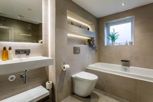a bathroom with a toilet and a sink and a tub at Arran Shores Luxury Shorefront Apartment 8 in Lamlash +11 photos