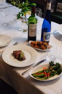 a table with plates of food and a bottle of wine at The White Hart in Wiveliscombe