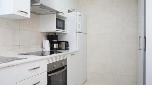 a kitchen with white cabinets and a refrigerator at Apartamentos BCL Playa Albir in Albir