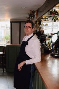 a man standing at a counter in a restaurant at The White Hart in Wiveliscombe