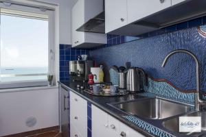 a kitchen with a sink and a blue tiled wall at La Suite 48 in Vietri sul Mare +9 photos