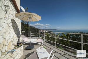 a balcony with an umbrella and chairs and the ocean at La Suite 48 in Vietri sul Mare