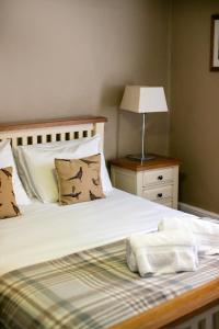 a bedroom with two beds and a lamp on a table at The White Hart in Wiveliscombe