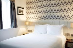 a bedroom with a white bed and a chevron wall at Fishermans Tavern in Dundee