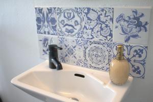 a bathroom sink with a soap dispenser and blue and white tiles at Landet Bed and Breakfast in Tomelilla +36 photos