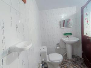 a white bathroom with a toilet and a sink at Vino lanka in Trincomalee